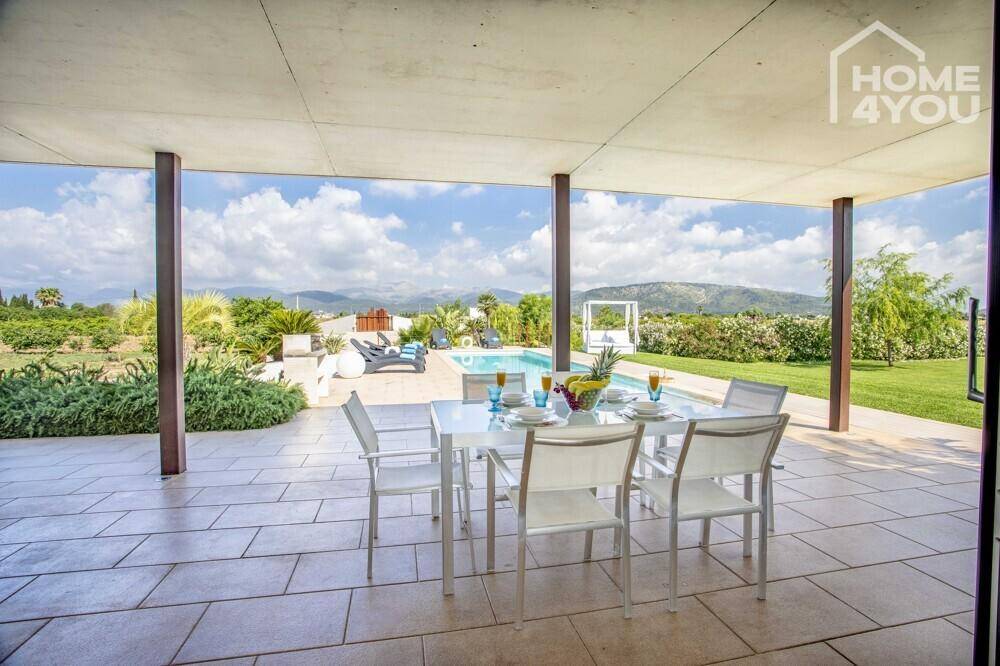 Überdachte Terrasse mit Esstisch, Blick auf den Pool und die umliegende Landschaft.
