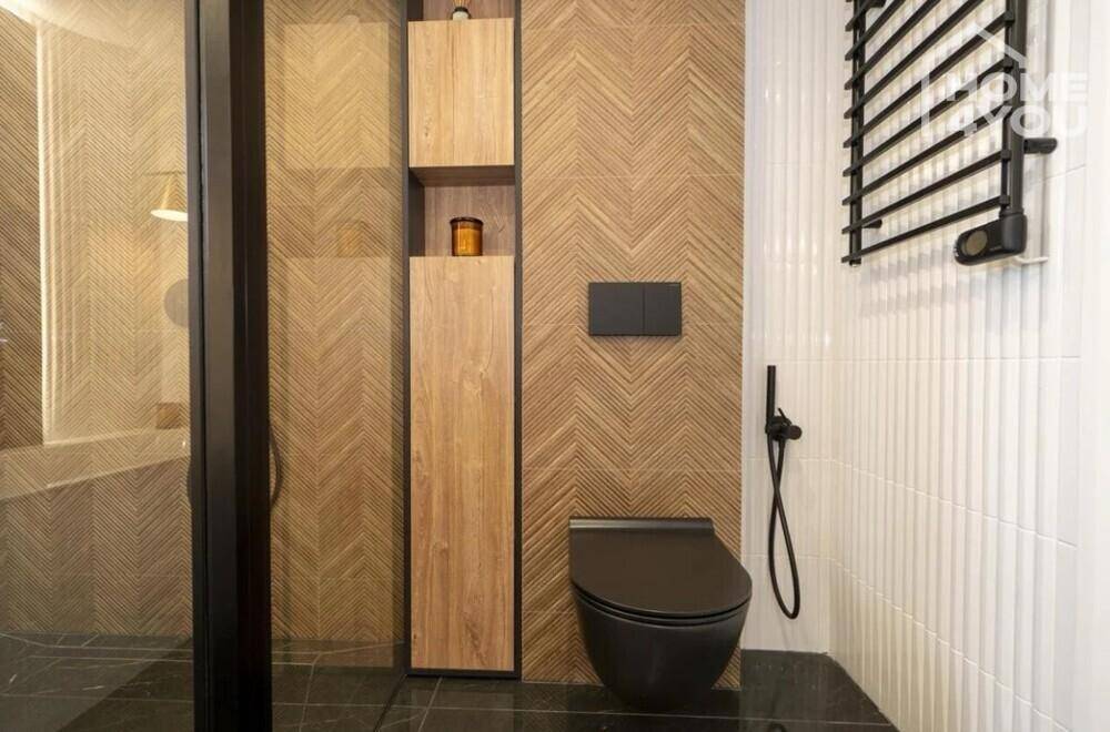 Modernes Badezimmer mit Holzfliesen, schwarzer Toilette und beheiztem Handtuchhalter.