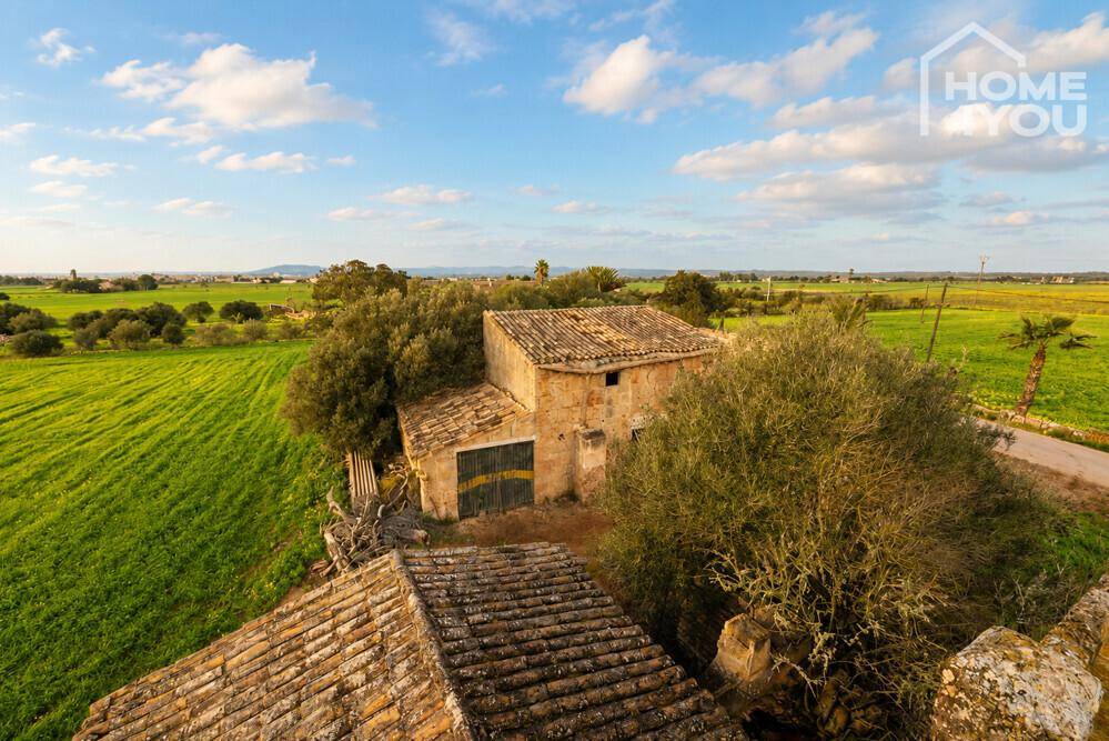Luftaufnahme des alten Bauernhauses mit Ziegeldach, umgeben von grünen Feldern und Bäumen.