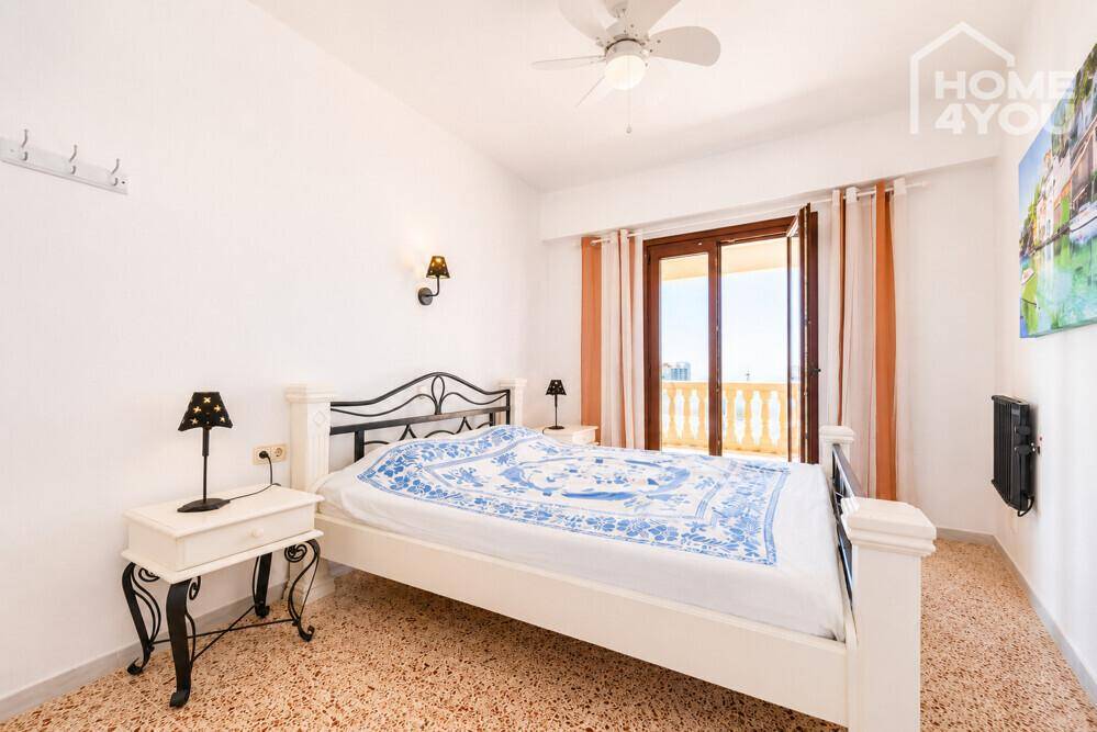 Schlafzimmer mit Doppelbett, Deckenventilator und Zugang zu einem Balkon.