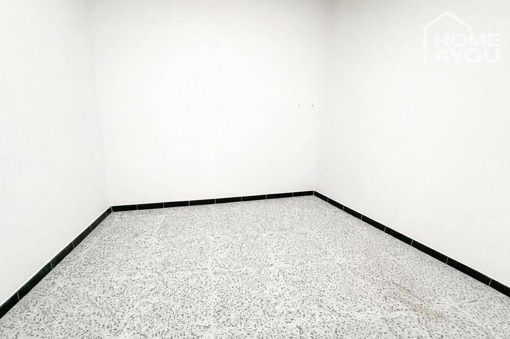 Kleiner, leerer Raum mit dunklem Fliesenboden und weißen Wänden, geeignet als Abstellraum oder Gästezimmer.