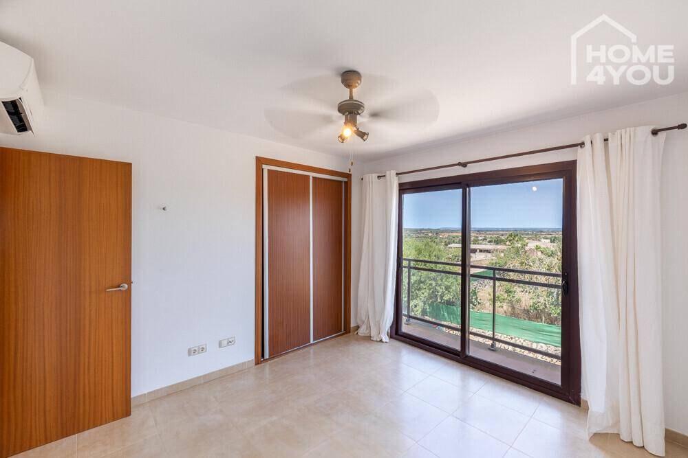 Schlafzimmer mit Einbauschrank, Klimaanlage und großen Schiebetüren mit Blick ins Grüne.
