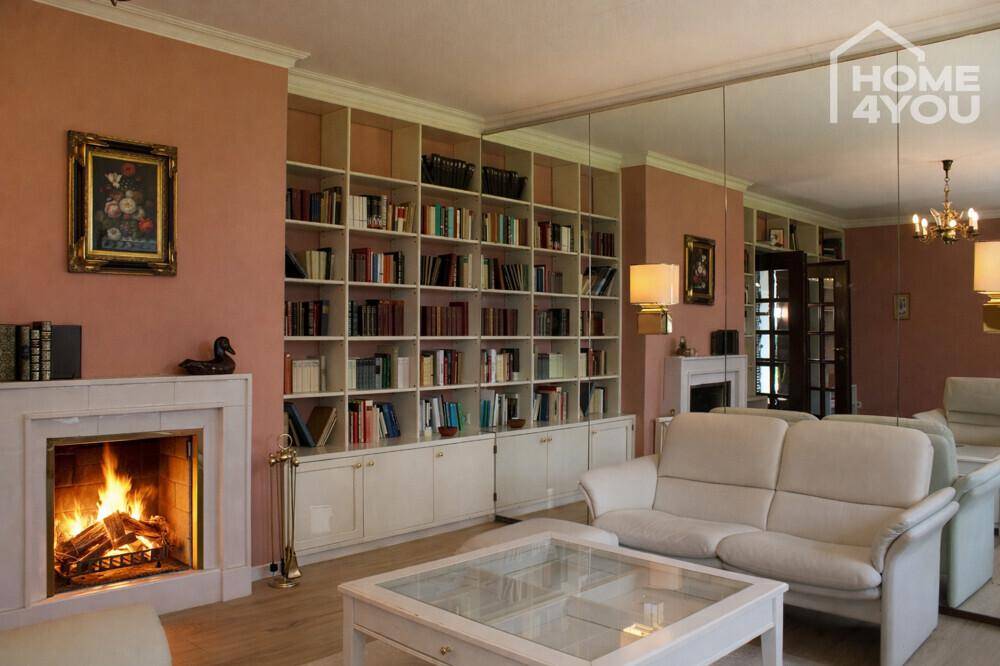 Elegantes Wohnzimmer mit Kamin, bequemen Sofas, Bücherregalen und Spiegelwand.