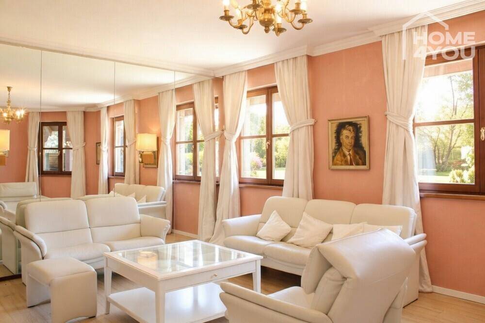 Helles Wohnzimmer mit weißen Sofas, großen Fenstern und rosa Wänden.