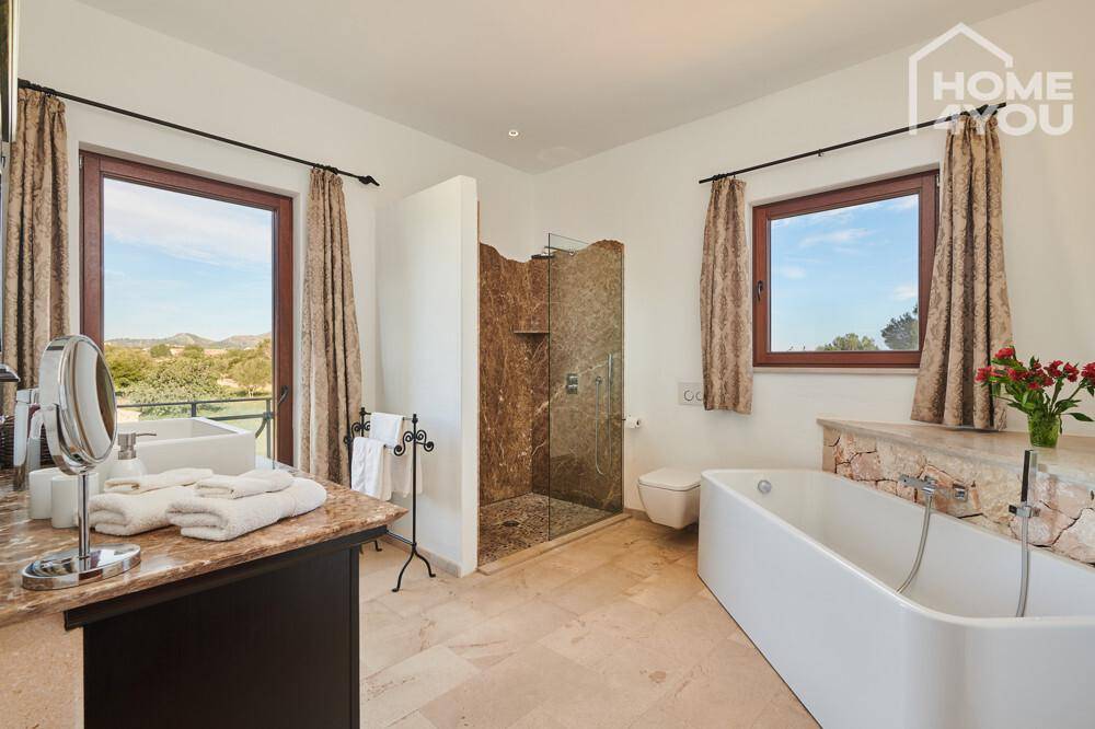 Geräumiges Badezimmer mit Badewanne, begehbarer Dusche und zwei Fenstern.