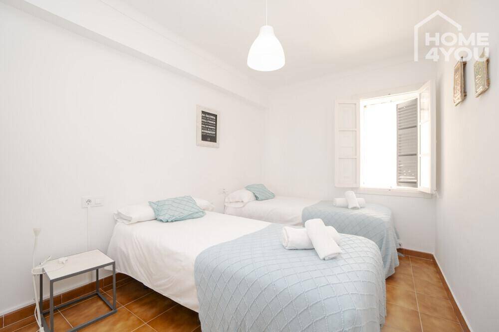 Gemütliches Schlafzimmer mit zwei Einzelbetten, frischer Bettwäsche und Fenster.