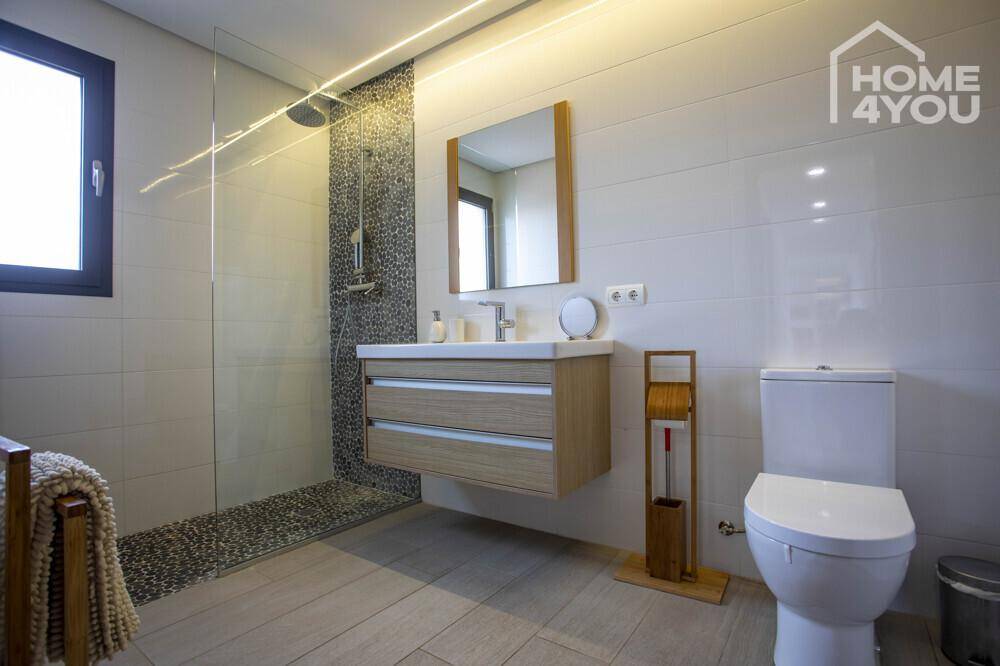 Modernes Badezimmer mit begehbarer Dusche, schwebendem Waschtisch und Fenster.