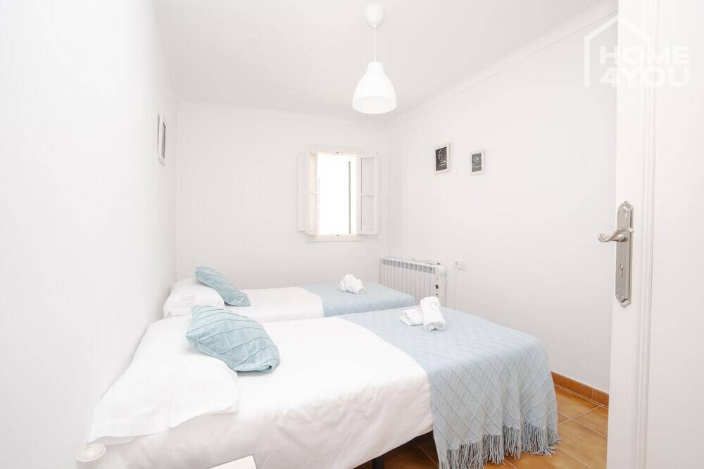 Schlafzimmer mit zwei Einzelbetten, Heizkörper und Fenster für natürliches Licht.