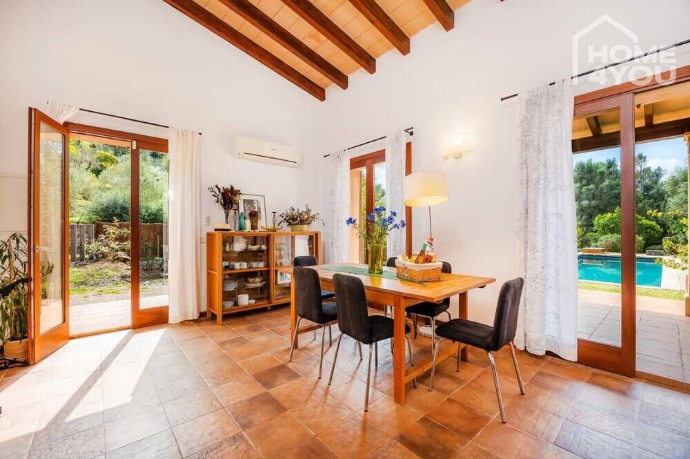 Heller Essbereich mit Holztisch, Terrakottaboden, Holzbalkendecke und Zugang zum Außenbereich.