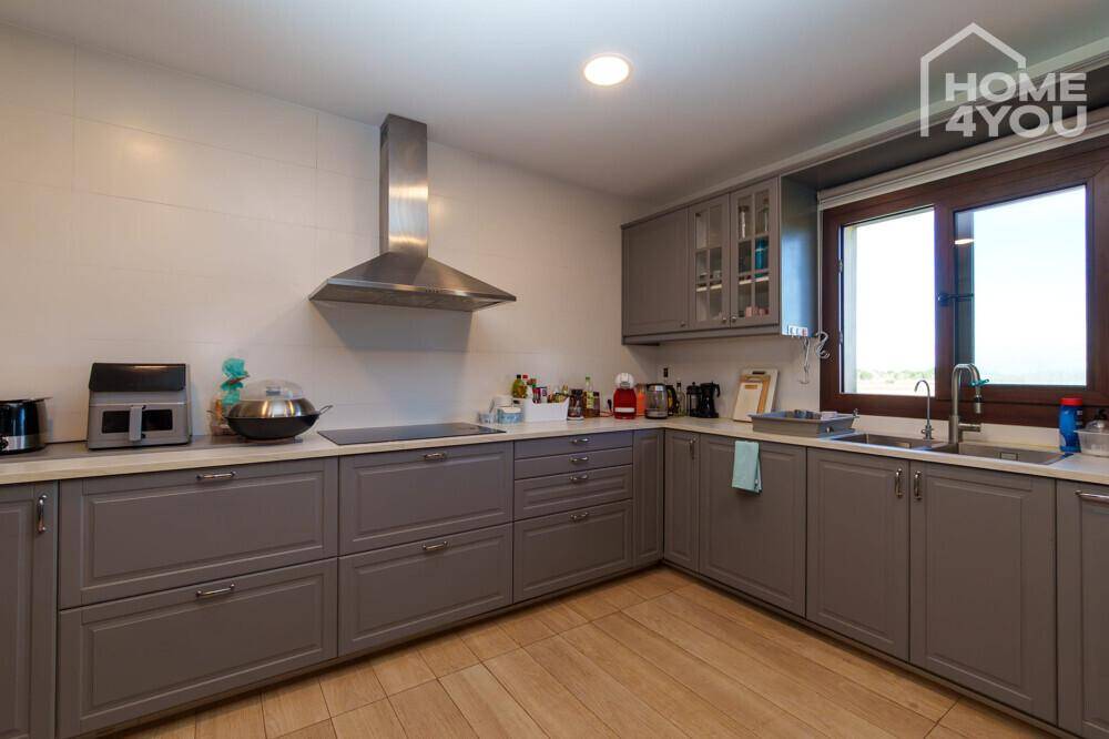 Funktionale Küche mit grauen Unterschränken, Spülbecken und einem Fenster für natürliches Licht.
