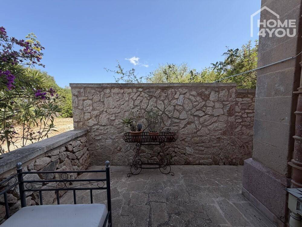 Kleiner, geschützter Terrassenbereich mit Steinmauer und dekorativem Pflanzentisch.