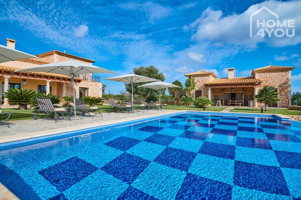 Weitläufiger Poolbereich mit Sonnenschirmen und separater Außenküche im mediterranen Stil.