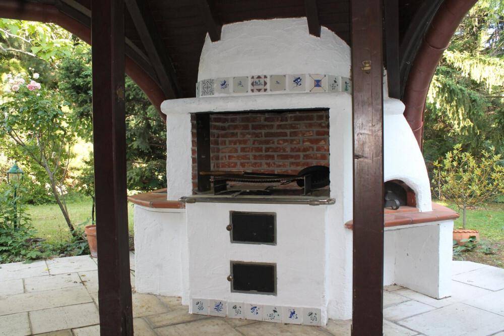 Gemauerter Grill- und Pizzaofen im Freien auf einer gepflasterten Terrasse.