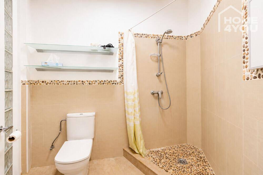 Badezimmer mit Dusche, WC und dekorativen Kieselsteinen an der Wand.