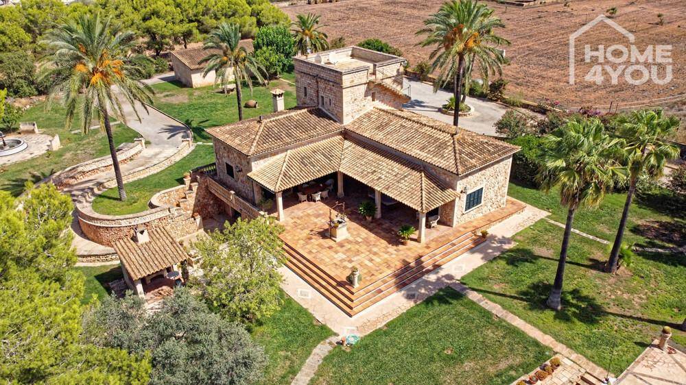 Vogelperspektive des Haupthauses mit traditioneller Architektur, großer Fliesenterrasse und gepflegtem Gartenbereich.