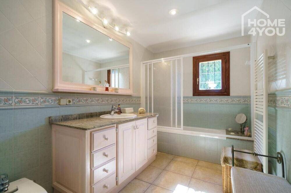 Geräumiges Badezimmer mit Badewanne, Einzelwaschbecken und hellblauen Fliesen.