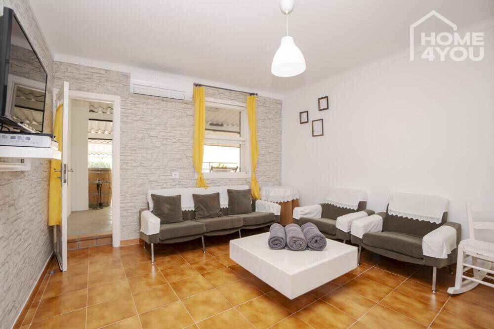 Gemütliches Wohnzimmer mit bequemen Sofas, Wandfernseher und einer strukturierten Akzentwand.
