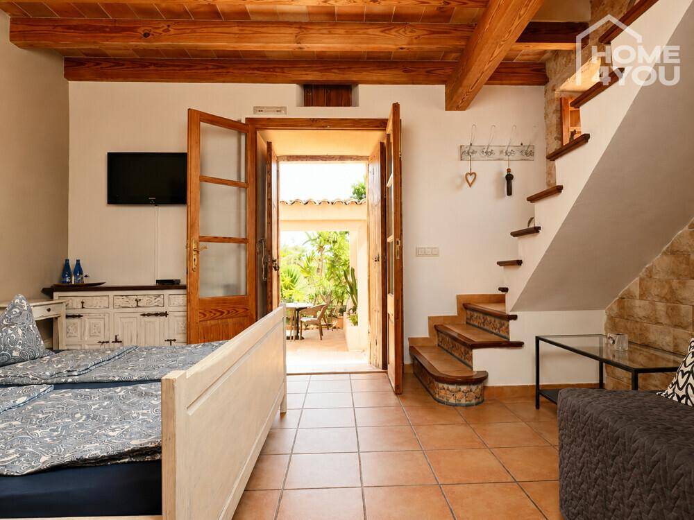 Rustikales Schlafzimmer mit Holzbalkendecke und direktem Zugang zum Gartenbereich.