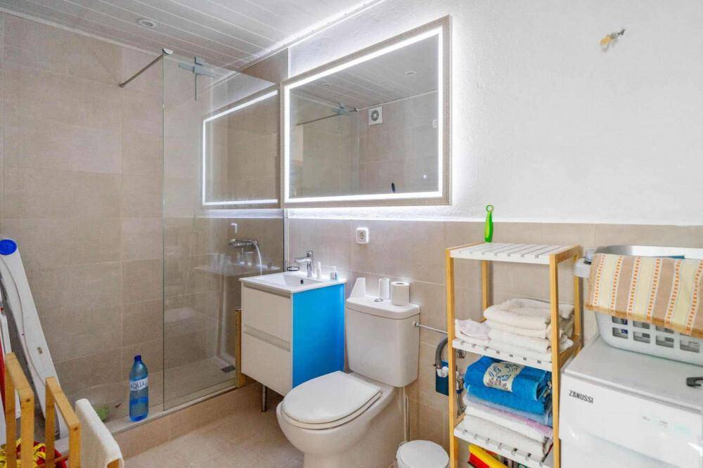 Modernes Badezimmer mit Duschkabine, Waschbecken und Toilette, inklusive Waschmaschine.