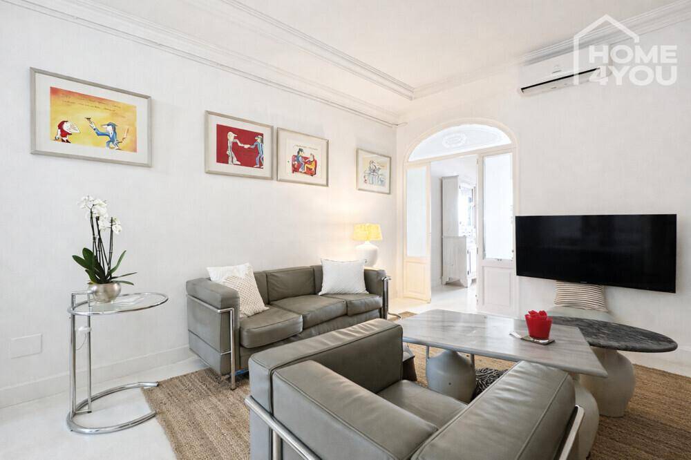Gemütliches Wohnzimmer mit modernen Ledersofas, Couchtisch und Kunstwerken an den Wänden.