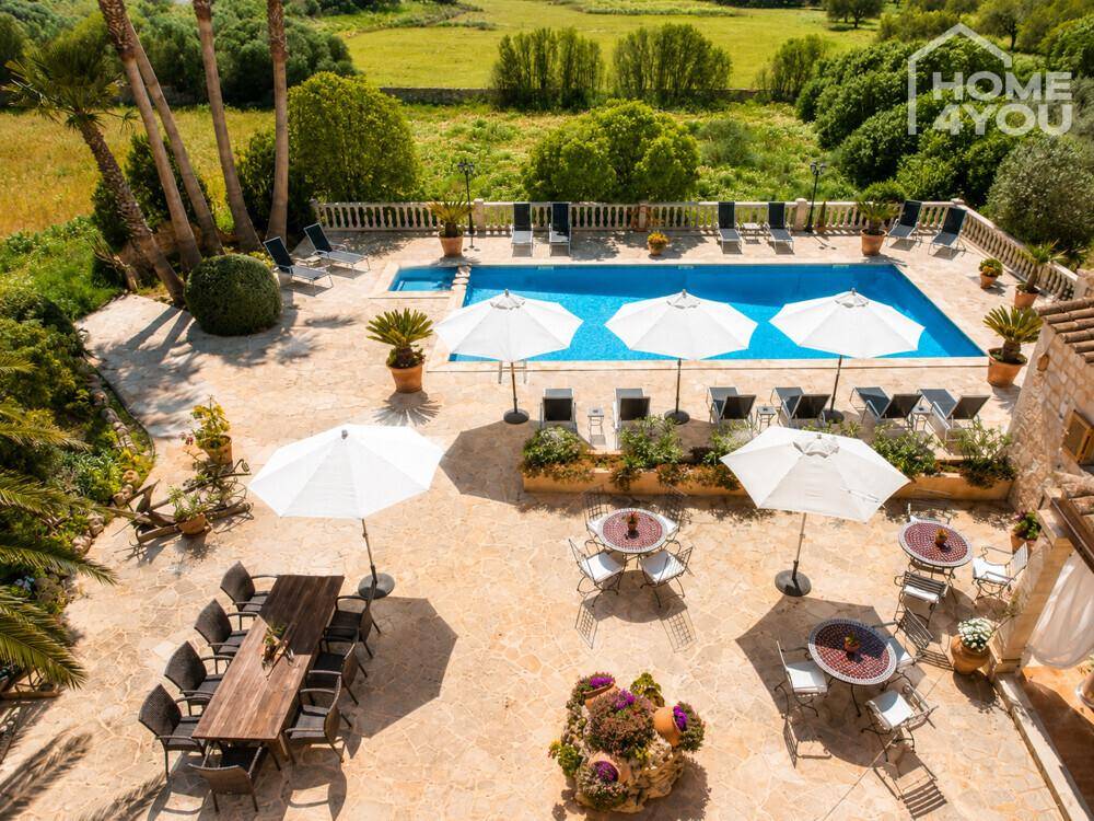 Weitläufige Poolterrasse mit mehreren Sitzbereichen und Blick auf die grüne Landschaft.