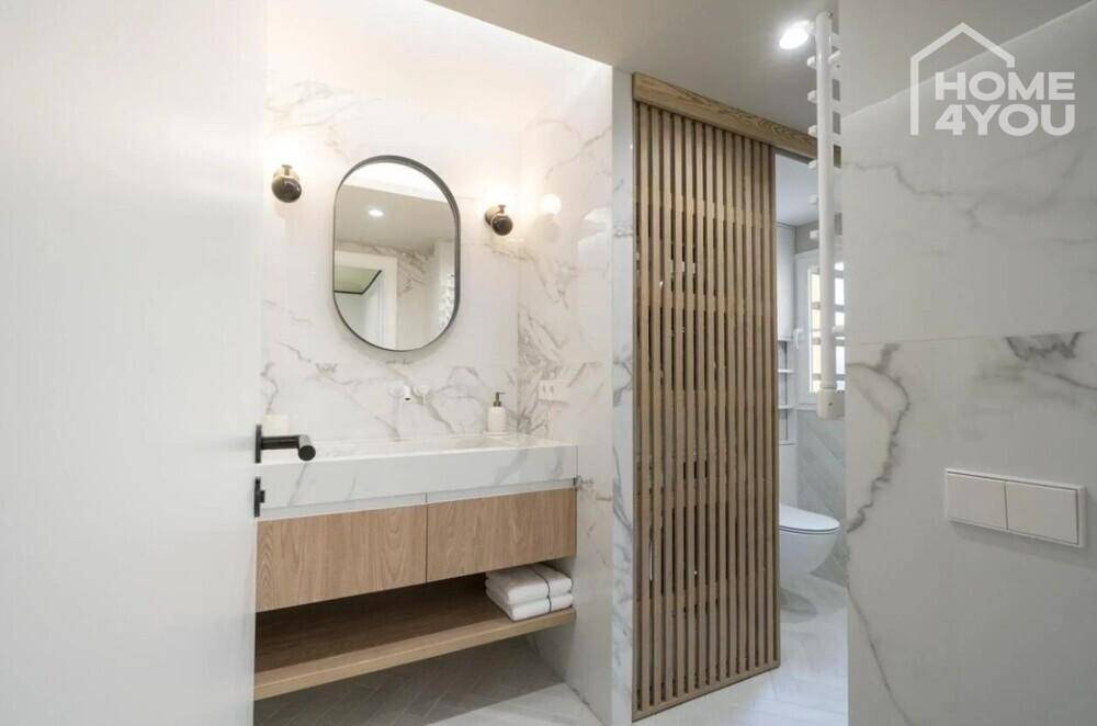 Stilvolles Badezimmer mit Marmorwänden, Holzlamellen und modernem Waschtisch.