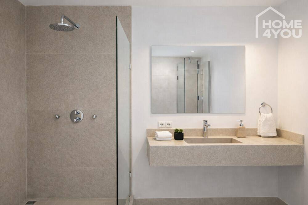 Modernes Badezimmer mit Regendusche, schwebendem Waschtisch und großem Spiegel.