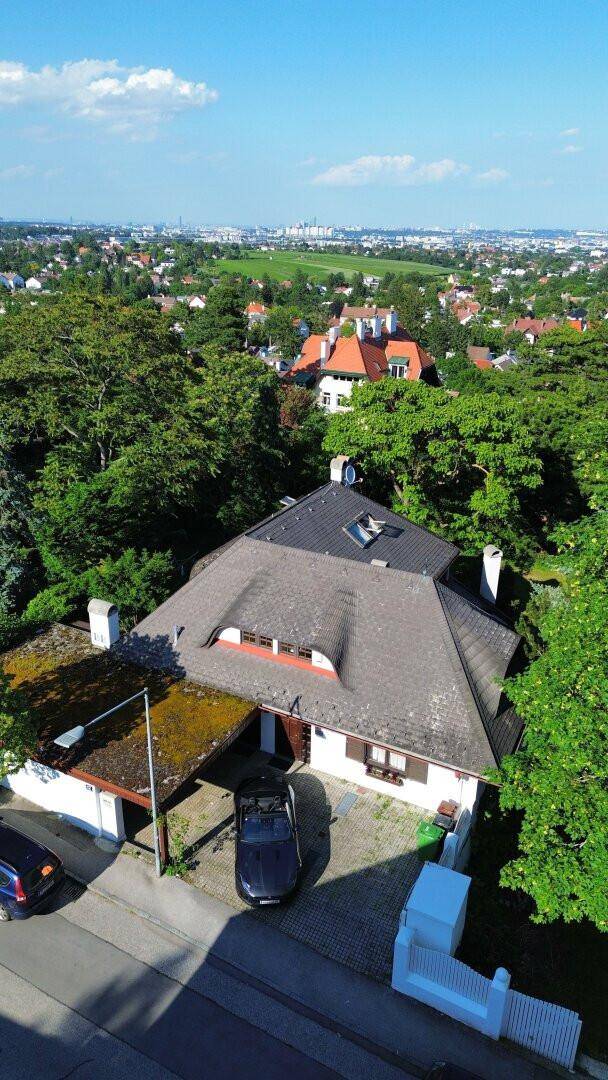 Luftaufnahme des Hauses mit Carport und der umliegenden Wohngegend mit Fernblick.