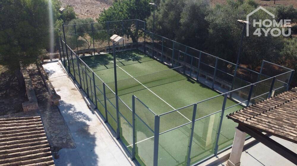 Professioneller Tennisplatz mit Kunstrasen und hoher Umzäunung auf dem Anwesen.