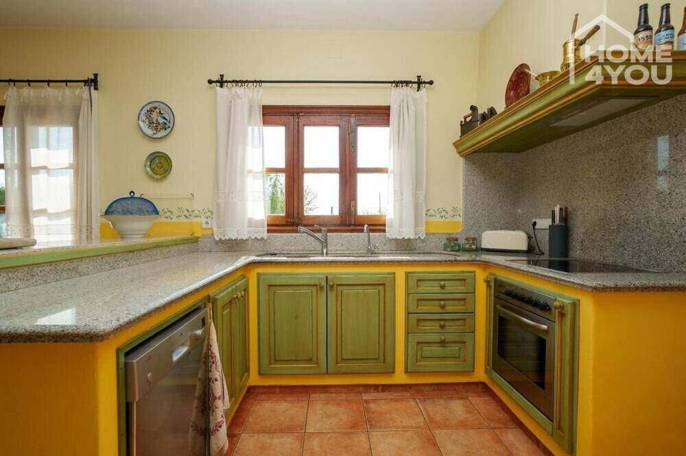 Rustikale Küche mit gelben und grünen Schränken, Granitarbeitsplatten und Fenster.