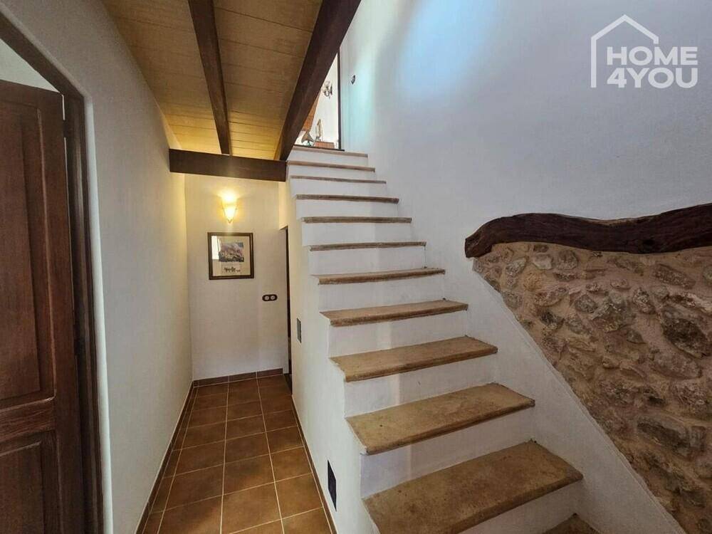 Treppenaufgang mit Steinstufen und einer rustikalen Steinwand im Flurbereich.