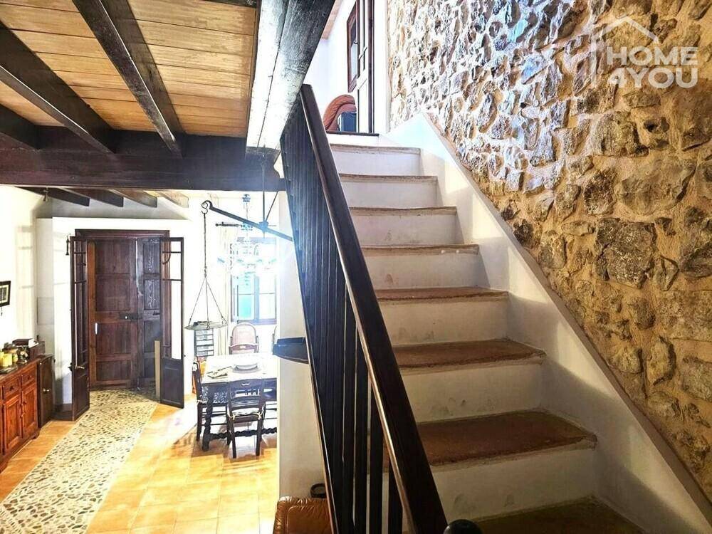 Geräumiger Wohn-Essbereich mit Steinfliesen, Holzbalkendecke und einer eleganten Treppe.