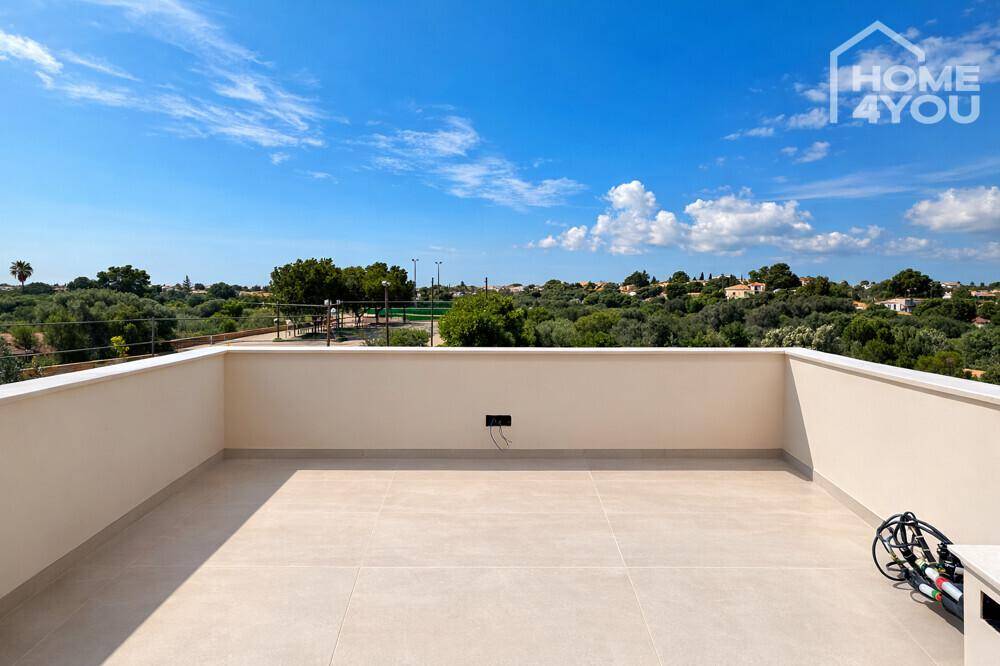 Weitläufige Dachterrasse mit Blick auf die grüne Umgebung und den blauen Himmel.