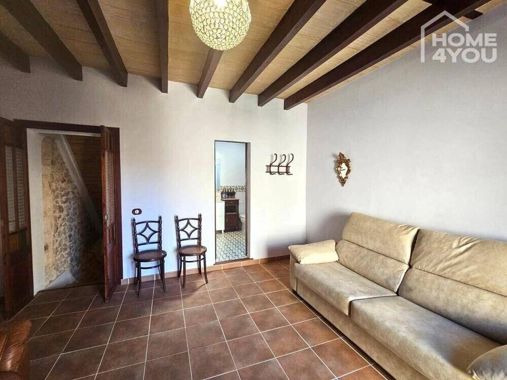 Geräumiges Wohnzimmer mit Holzbalkendecke, Fliesenboden und traditioneller Einrichtung.