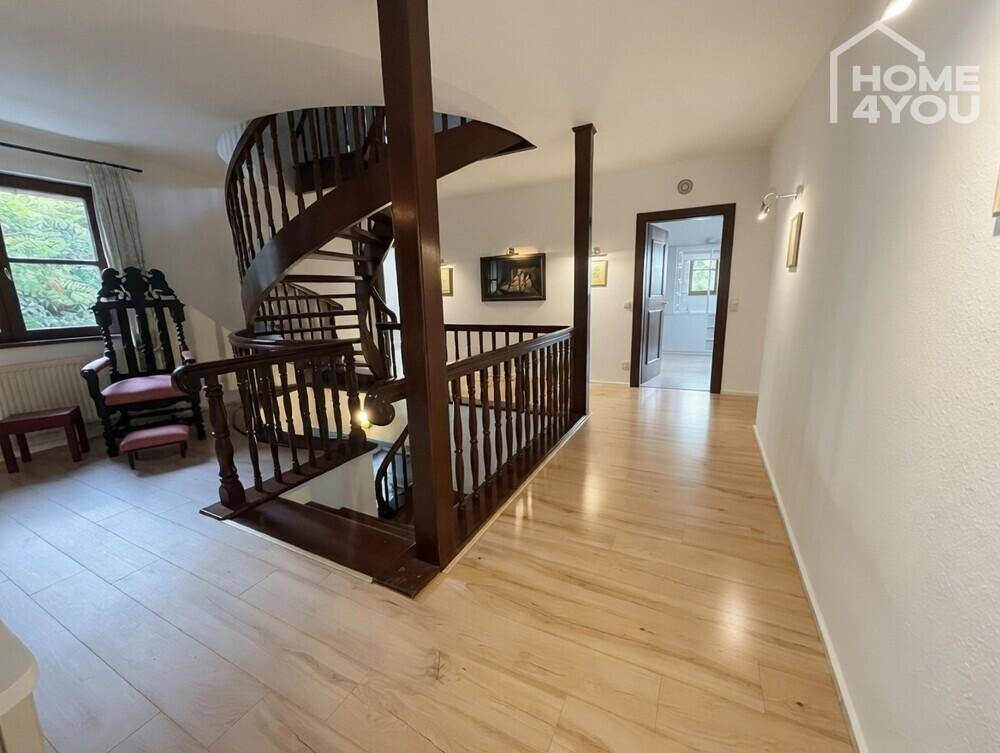 Heller Flur mit eleganter Holzwendeltreppe und hellem Holzboden.