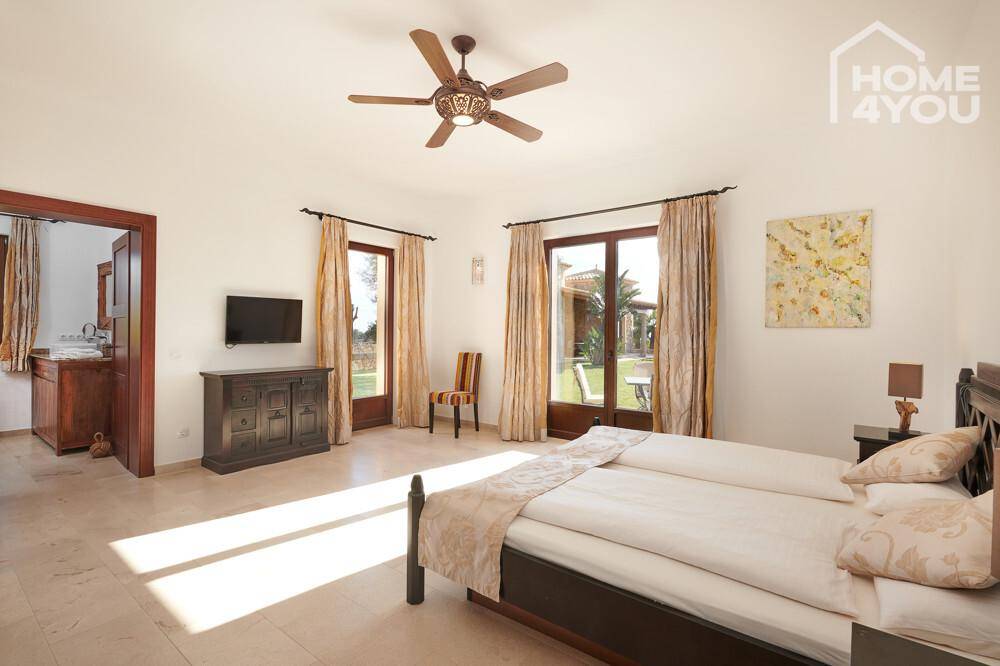 Helles Schlafzimmer mit Doppelbett, Deckenventilator und Zugang zum Garten.
