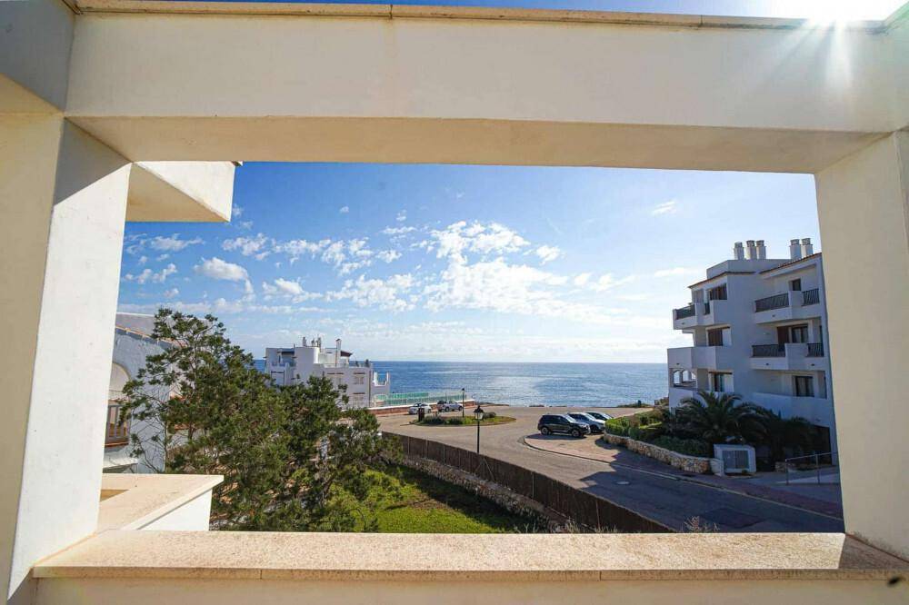 Blick vom Balkon auf die Küstenlandschaft mit Gebäuden, Straße und dem weiten Meer.