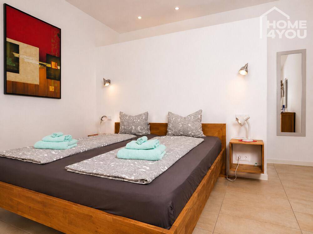Modern eingerichtetes Schlafzimmer mit Holzbett und minimalistischer Dekoration.