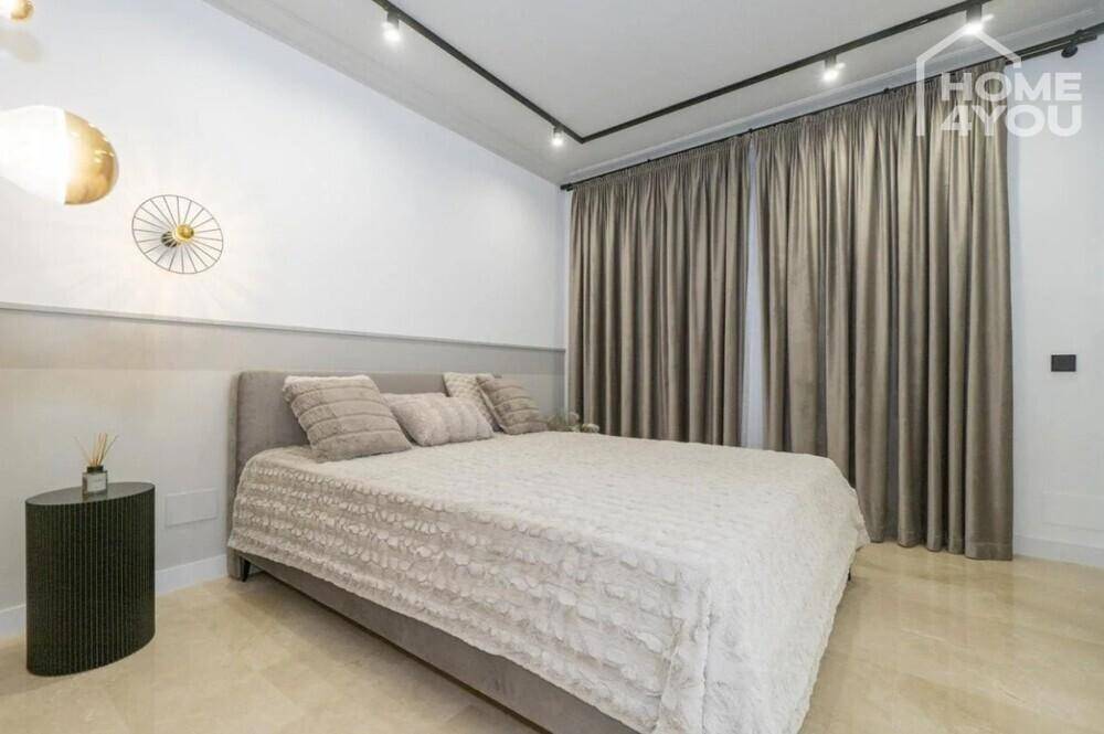 Komfortables Schlafzimmer mit Doppelbett, eleganten Vorhängen und modernen Wandleuchten.