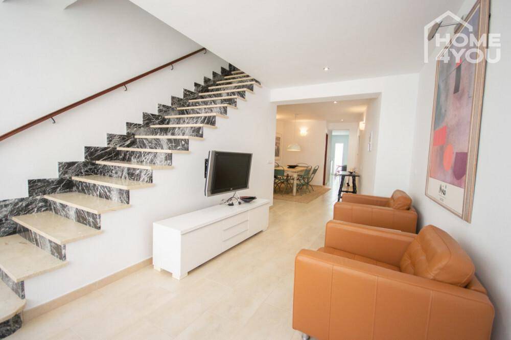 Geräumiger Wohnbereich mit eleganter Marmortreppe, Ledersesseln und Blick zum Esszimmer.