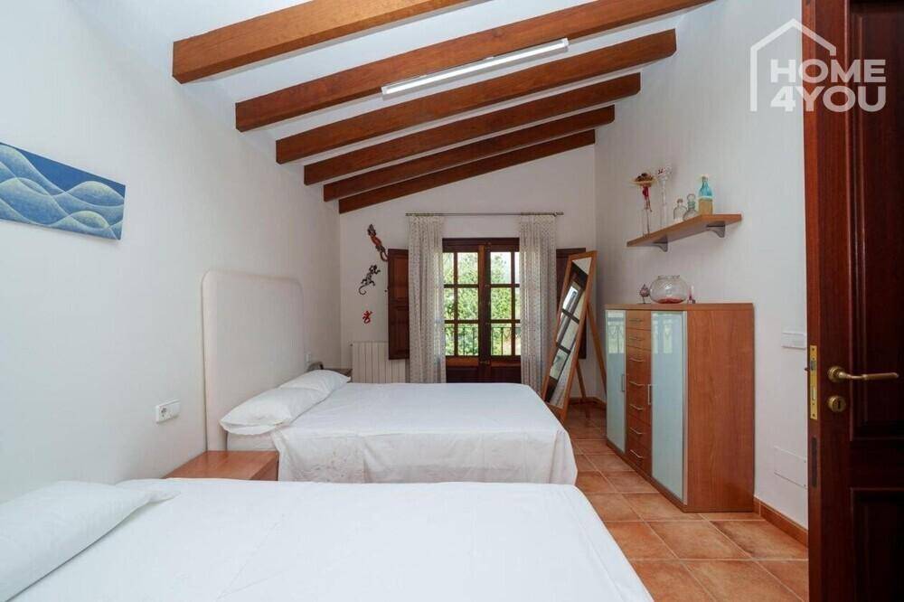 Helles Schlafzimmer mit zwei Einzelbetten, Holzbalkendecke und Terrakottaboden.