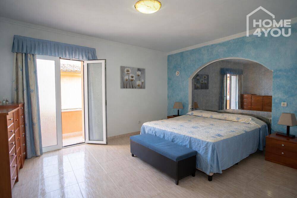 Geräumiges Schlafzimmer mit Doppelbett, blauen Akzenten und Zugang zu einem Balkon.