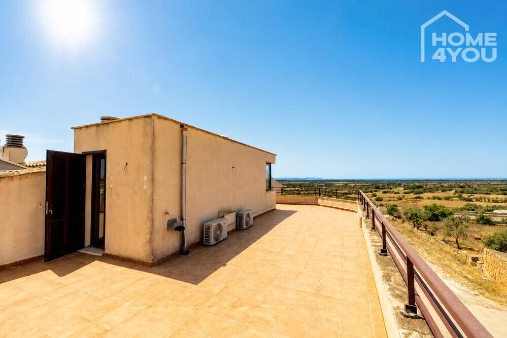 Große Dachterrasse mit weitem Blick über die Landschaft bis zum Meer unter blauem Himmel.