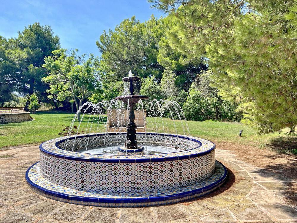 Malerischer Brunnen mit kunstvollen Fliesen und üppigem Grün, der eine ruhige Atmosphäre schafft.