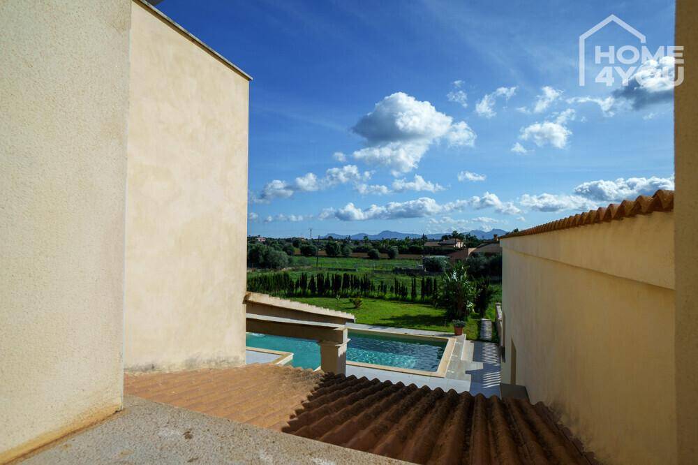 Panoramablick von der oberen Etage auf den Poolbereich und die umliegende grüne Landschaft.