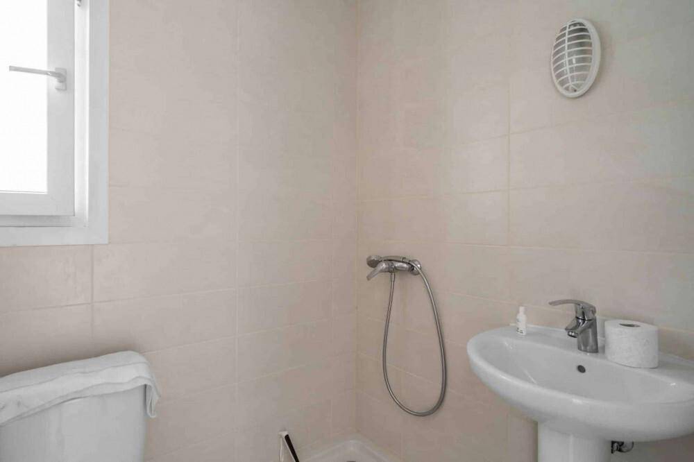 Helles Badezimmer mit Waschbecken, Toilette und Duschbereich, ausgestattet mit Fliesen.