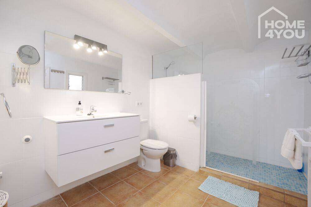 Modernes Badezimmer mit schwebendem Waschtisch, Toilette und begehbarer Dusche.