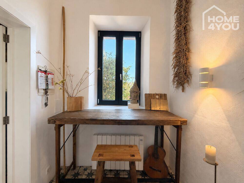 Heller Eingangsbereich mit Holztisch, Fenster und dekorativen Elementen.