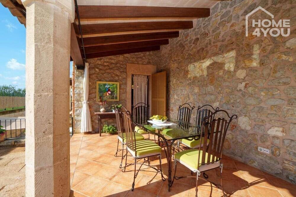 Überdachte Terrasse mit schmiedeeisernen Möbeln und Blick auf die grüne Umgebung.