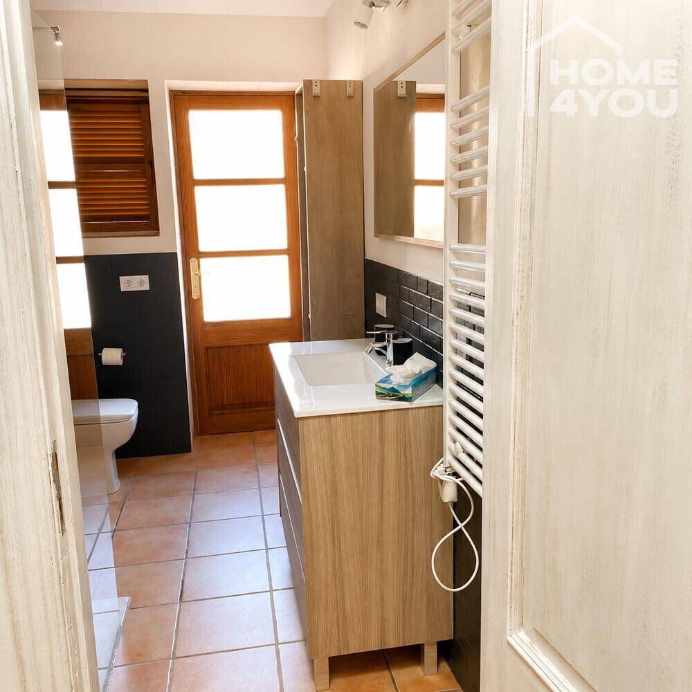 Modernes Badezimmer mit Holzwaschtisch, Toilette und beheiztem Handtuchhalter.